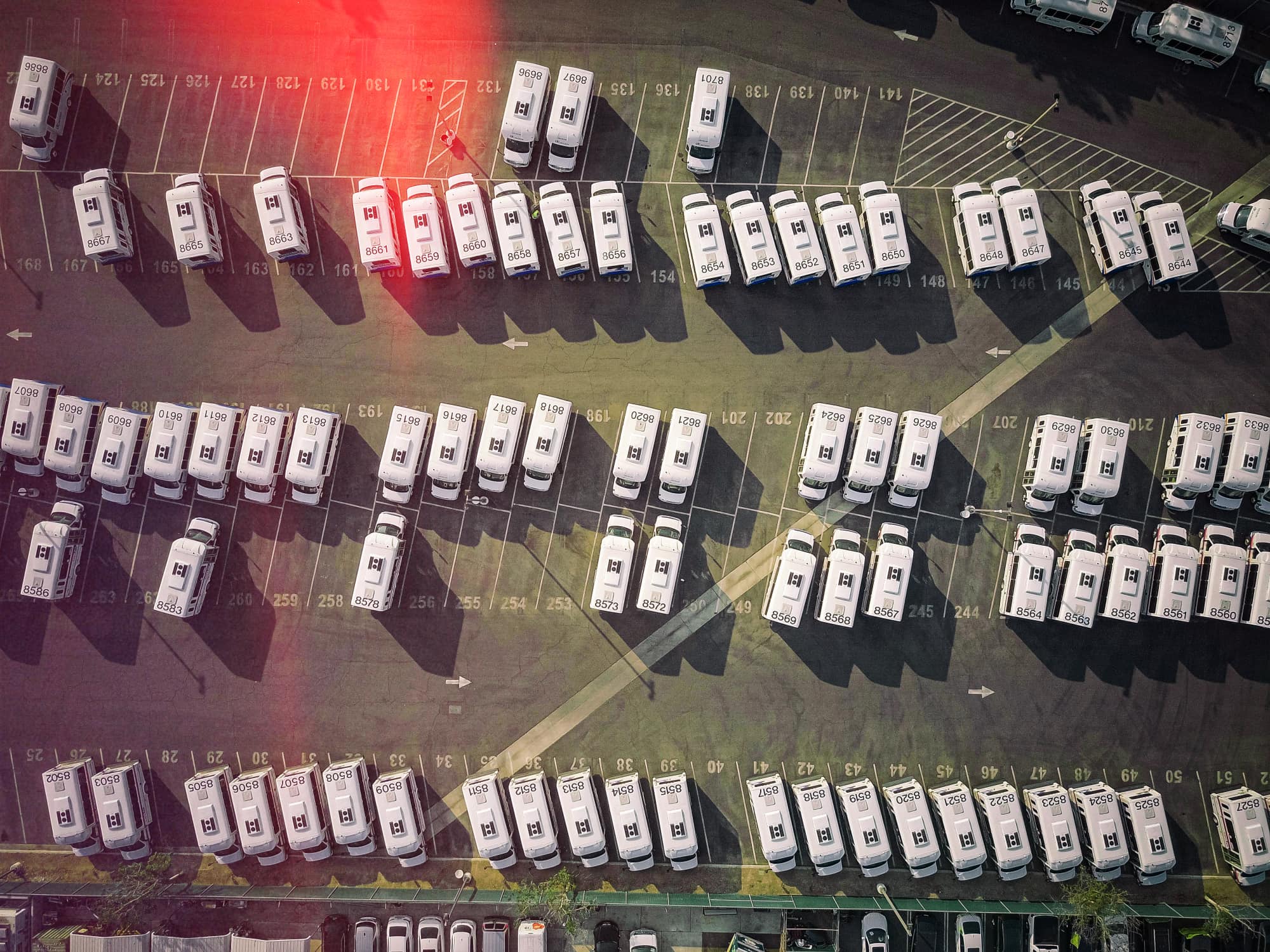 Aerial view of a large van fleet parked in numbered bays at a depot.